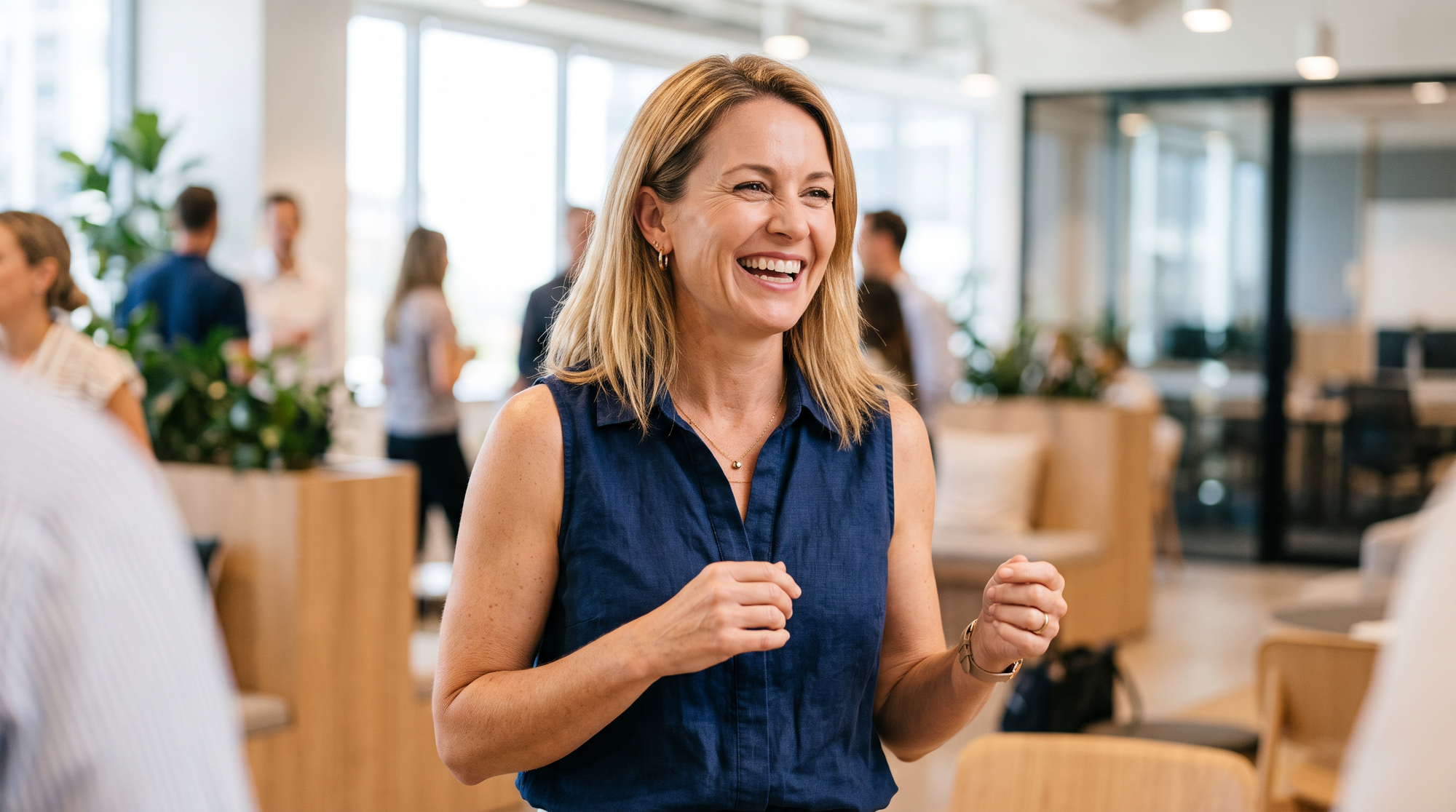 Confident woman laughing with ease at a bright office gathering, relaxed and comfortable